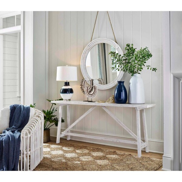 White wood console table with a glass lamp
